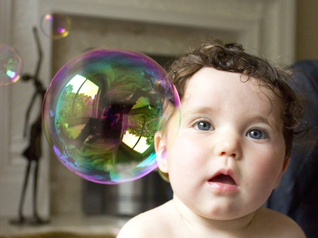 An open-mouthed infant with a floating bubble